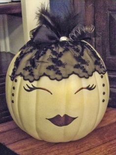 a white pumpkin with black lace on it sitting on a wooden table next to a door