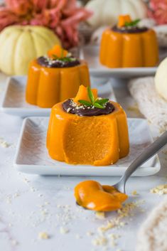 small desserts on white plates with pumpkins in the background and spoon next to them