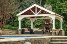 an outdoor living area with fireplace, couches and table next to a swimming pool