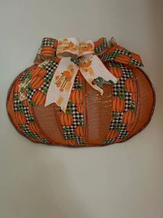 an orange pumpkin shaped purse with a bow on the front and plaid ribbon around it