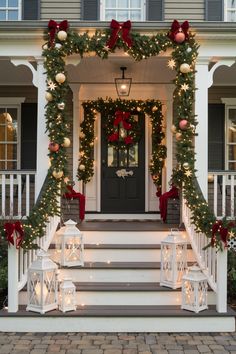 a front porch decorated for christmas with wreaths and lights on the steps, lanterns lit up