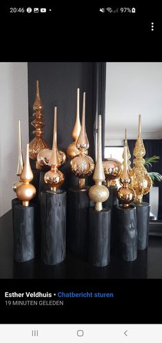 there are many black vases with gold decorations in them on the table next to each other