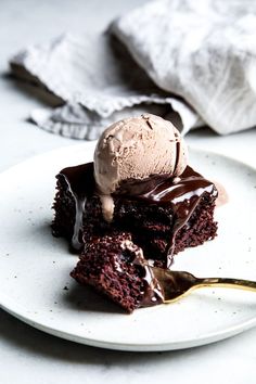 a piece of chocolate cake with ice cream on top is sitting on a white plate