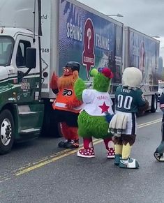 some people are standing in front of a large truck with the same mascot on it