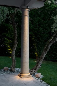 an outdoor patio area with stone steps and trees at night, lit by lights on the pillars