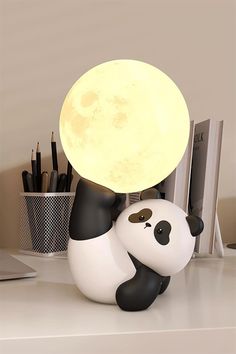 a panda bear lamp with a full moon on it's head sitting on a desk