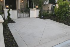 a concrete patio with wrought iron fence and planters in front of the entrance to a house