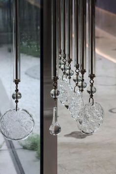 a wind chime hanging from the side of a glass window next to a sidewalk