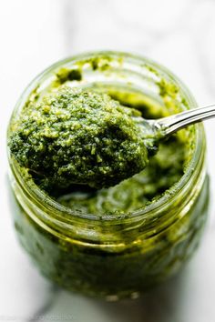 a spoon full of pesto sauce in a jar