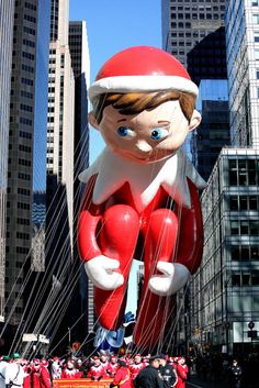 a large inflatable santa clause balloon floats through the air with other floaters