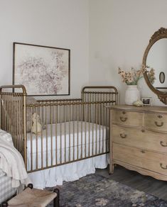 a baby crib in a bedroom with a dresser and mirror on the wall above it