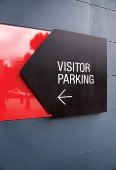 a sign on the side of a building that says visitor parking with an arrow pointing to the right