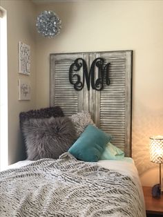 a bed with pillows and blankets on top of it next to a night stand in front of a window