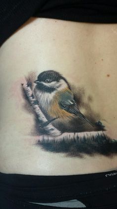 a woman's stomach with a small bird on top of the belly tattoo design