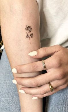 a woman's arm with a small rose tattoo on the left side of her arm