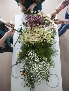 three women are arranging flowers on a table