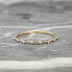 a yellow gold wedding band with five diamonds on it, sitting on a marble surface