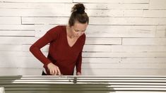 a woman in red shirt cutting into a piece of furniture with scissors and pliers