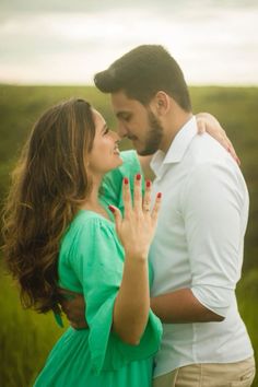 a man and woman are standing in the grass with their hands on each other's chest