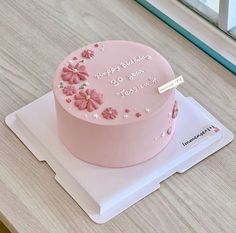 a pink birthday cake with flowers on it