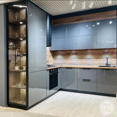 an empty kitchen with stainless steel appliances and wood accents on the walls, along with glass shelves