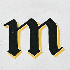 the letter m is made up of black and yellow letters on a white surface with gold trim