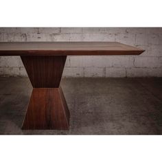 a large wooden table sitting on top of a cement floor next to a brick wall