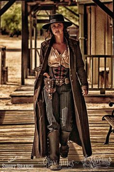 a woman dressed in steampunk clothing walking down a wooden walkway