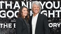 two people standing next to each other in front of a black and white sign that says thank you, good night