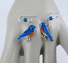 You'll be singing the blues in a good way with these handmade artisan Bluebird earrings, each crafted of sterling silver and brass and hand painted with a glass bead on the hook. They measure 1.5 inches in length from hook to tail and are 5/8 inches wide. The dangle earrings are lightweight, vibrantly colored, new, and in excellent condition with a signature by the artist on the back. Spring Jewelry, Le Crochet, Bird Lover, Bird Lovers, Handmade Artisan, Glass Bead, Blue Bird, Earrings Handmade, Belly Button Rings