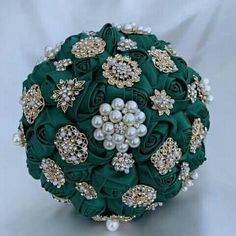 a green bridal bouquet with pearls and brooches on it's side