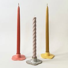 three candles sitting next to each other on top of a white surface with one candle in the middle