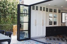 a kitchen with black and white tile flooring next to an outdoor dining area that has sliding glass doors