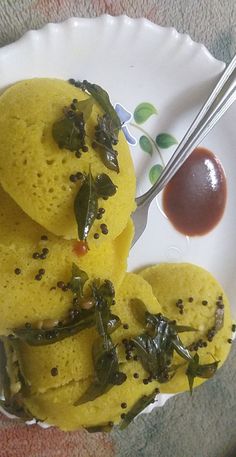 some food is sitting on a plate with spoons and sauce in the bowl next to it