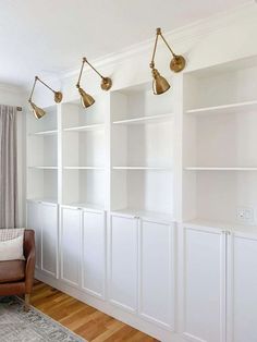 a living room filled with furniture and lots of white bookshelves next to a window