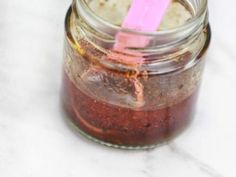 a jar filled with food sitting on top of a white counter next to a pink straw