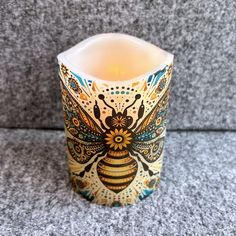 a candle that is sitting on top of a table in front of a gray wall