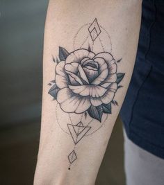 a black and white rose tattoo on the right arm, with geometric shapes around it