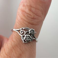 a close up of a person's hand wearing a ring with flowers on it