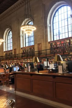 the large library has many bookshelves and desks with laptops on them