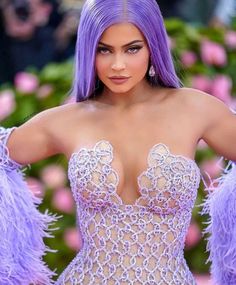 a woman with purple hair wearing a corset and feathered dress in front of flowers