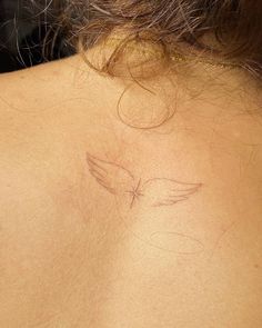 the back of a woman's neck with an angel tattoo on it