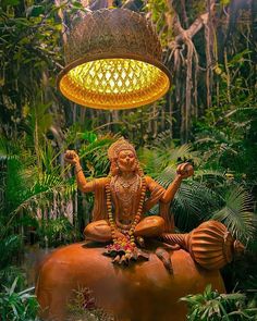 an elephant statue with a light hanging from it's head in the middle of jungle