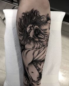 a man's leg with a black and white tattoo design on it, featuring a lion