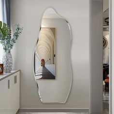 a mirror that is on the side of a wall next to a vase with flowers in it