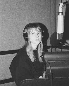 a woman wearing headphones sitting in front of a microphone