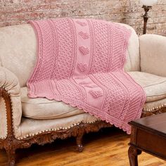 a couch with a pink knitted blanket on it