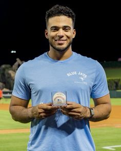 a man standing on top of a baseball field holding a glass in front of him