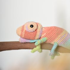 a crocheted chamelon is sitting on a branch