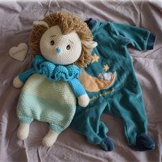 a crocheted doll laying on top of a bed next to a stuffed animal